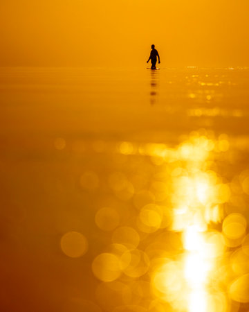A beautiful sunset scenery with a man silhouette going for a swim in Baltic Sea. Summer evening at the beach.の写真素材