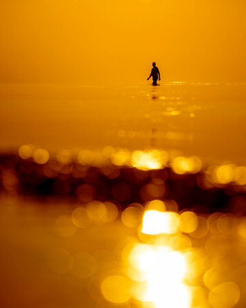 A beautiful sunset scenery with a man silhouette going for a swim in Baltic Sea. Summer evening at the beach.の写真素材