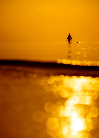 A beautiful sunset scenery with a man silhouette going for a swim in Baltic Sea. Summer evening at the beach.の写真素材
