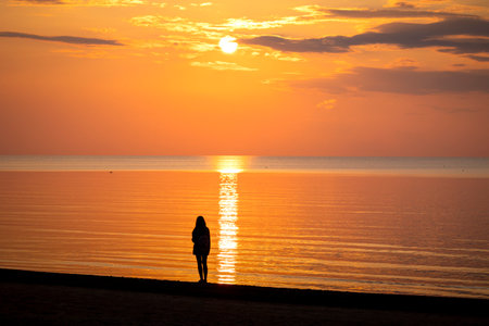 A beautiful summer sunset scenery with people silhouettes walking on a beach, enjoying Baltic Sea costline. Evening landscape of Latvia, Europe.の写真素材