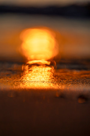 A beautiful shallow depth of field photograph of sunset sunrays reflecting in the beach sand. Summer...