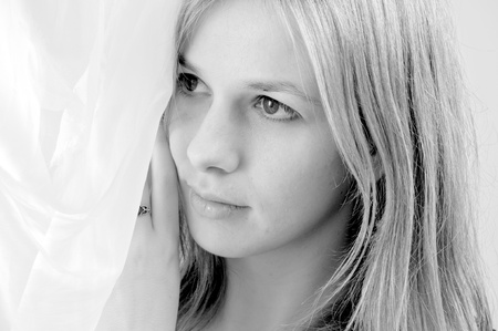 portrait of an attractive beautiful blond woman  under the curtainsの写真素材