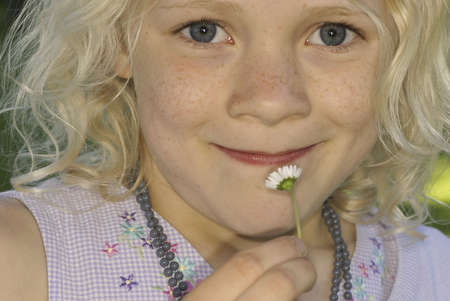 Small girl smelling a flower , smiling closeup