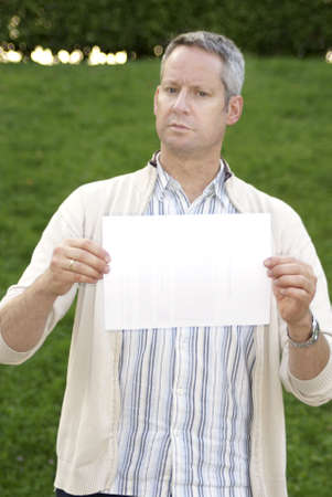 Young male standing and holding a blank signの写真素材