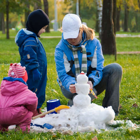 Mother and her children playing with first snow in the park.の写真素材