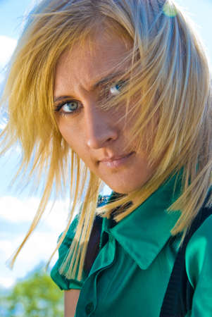 Stylish cute blonde with fly-away hair. Portrait on sky background.の写真素材