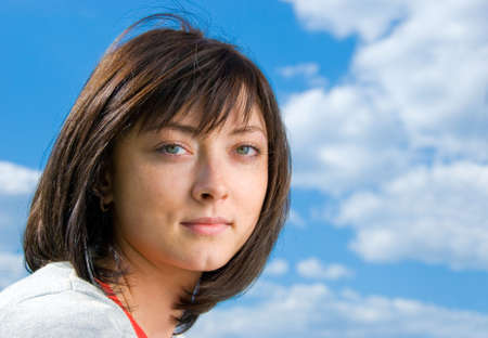 Cute brunette portrait on the sky background.の写真素材