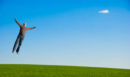 Happy stout man jumping over green grass field. の写真素材