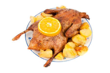 Baked duck with sliced orange and potatoes on a plate isolated over whiteの写真素材