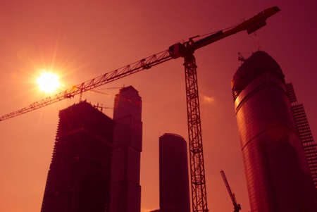 Sky-scrapers construction. Cranes and buildings over red sky.
の写真素材