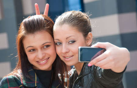Two happy girls make self-portrait on a street