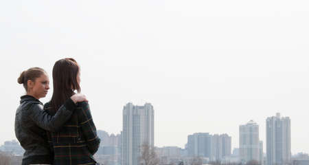 Two young girls looking to a big city panoramaの写真素材