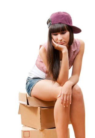 Sad girl sitting on cardboard boxes isolated over whiteの写真素材
