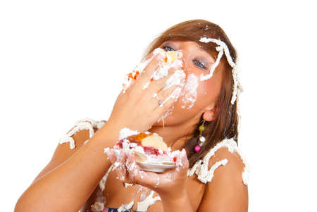 Girl eating cake with his hands, her face and head stained cream. の写真素材