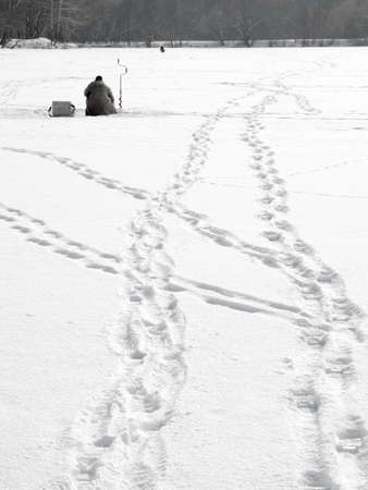 Man ice fishing on the river at winterの写真素材