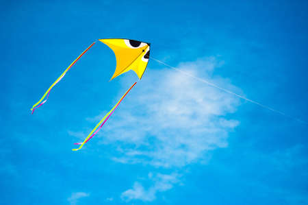 Yellow kite flying in the blue skyの写真素材