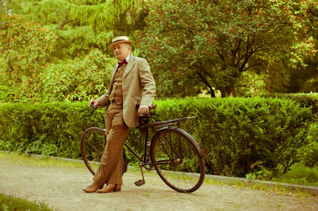 Mature man posing with retro bicycle in the park. Vintage style.の写真素材