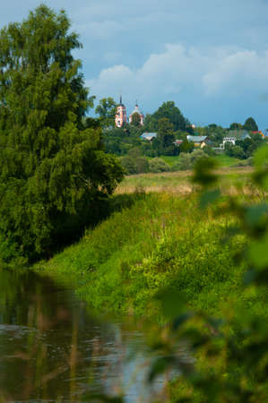 Typical Russian village landscape with the river and the church in the distanceの写真素材