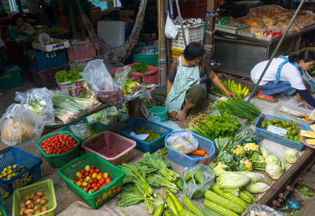 MAEKLONG, THAILAND - MARCH 24: Vendor sells fresh local agricultural production on March 24, 2014 in famous Maeklong Railway Market also known as Talad Rom Hub or Umbrella Pulldown Marketのeditorial素材