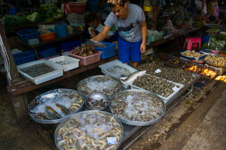 MAEKLONG, THAILAND - MARCH 24: Vendor sells fresh local fishery production on March 24, 2014 in famous Maeklong Railway Market also known as Talad Rom Hub or Umbrella Pulldown Marketのeditorial素材