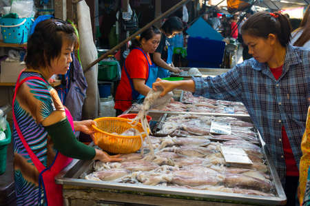 MAEKLONG, THAILAND - MARCH 24: Vendor sells fresh local fishery production on March 24, 2014 in famous Maeklong Railway Market also known as Talad Rom Hub or Umbrella Pulldown Marketのeditorial素材