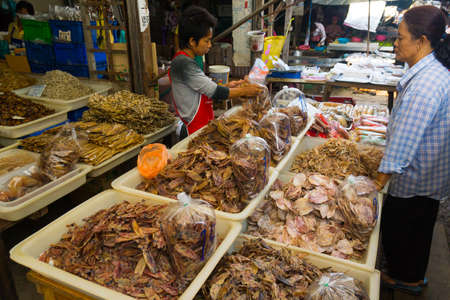MAEKLONG, THAILAND - MARCH 24: Vendor sells dried local fishery production on March 24, 2014 in famous Maeklong Railway Market also known as Talad Rom Hub or Umbrella Pulldown Marketのeditorial素材