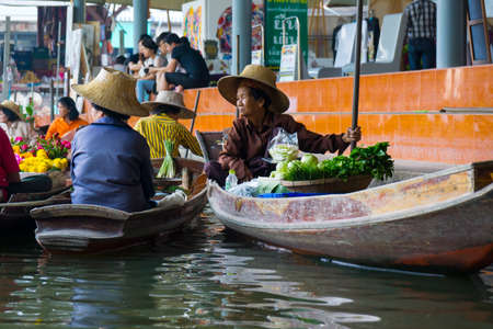 RATCHABURI, THAILAND - MARCH 24: Local peoples sell fruits, food and souvenirs at famous tourist attraction Damnoen Saduak floating market on March 24, 2014 in Ratchaburi, Thailand.のeditorial素材
