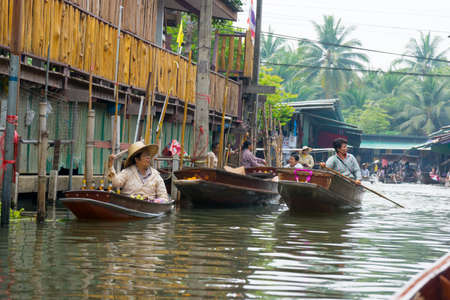 RATCHABURI, THAILAND - MARCH 24: Local peoples sell fruits, food and souvenirs at famous tourist attraction Damnoen Saduak floating market on March 24, 2014 in Ratchaburi, Thailand.のeditorial素材