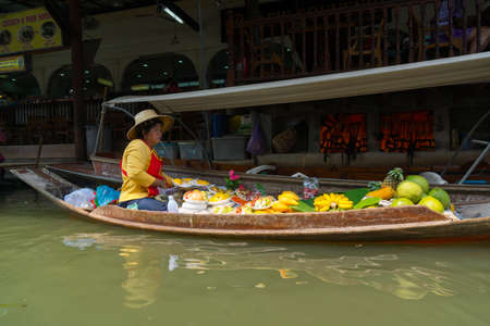 RATCHABURI, THAILAND - MARCH 24: Local peoples sell fruits, food and souvenirs at famous tourist attraction Damnoen Saduak floating market on March 24, 2014 in Ratchaburi, Thailand.のeditorial素材
