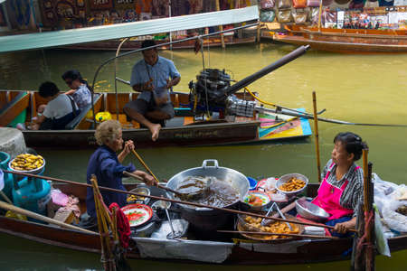 RATCHABURI, THAILAND - MARCH 24: Local peoples sell fruits, food and souvenirs at famous tourist attraction Damnoen Saduak floating market on March 24, 2014 in Ratchaburi, Thailand.のeditorial素材