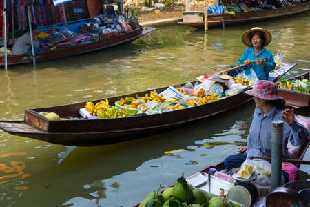 RATCHABURI, THAILAND - MARCH 24: Local peoples sell fruits, food and souvenirs at famous tourist attraction Damnoen Saduak floating market on March 24, 2014 in Ratchaburi, Thailand.のeditorial素材