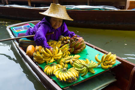 RATCHABURI, THAILAND - MARCH 24: Local peoples sell fruits, food and souvenirs at famous tourist attraction Damnoen Saduak floating market on March 24, 2014 in Ratchaburi, Thailand.のeditorial素材
