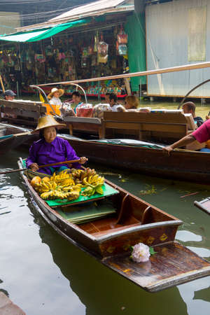 RATCHABURI, THAILAND - MARCH 24: Local peoples sell fruits, food and souvenirs at famous tourist attraction Damnoen Saduak floating market on March 24, 2014 in Ratchaburi, Thailand.のeditorial素材