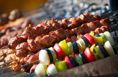 Prepared shashlik, lamb meat grilling on metal skewer and grilled vegetablesの写真素材