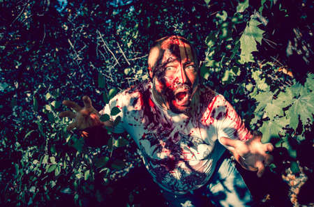 Man zombie walking dead outdoors. Dark lighting. Color was changed to emphasize the atmosphere of...