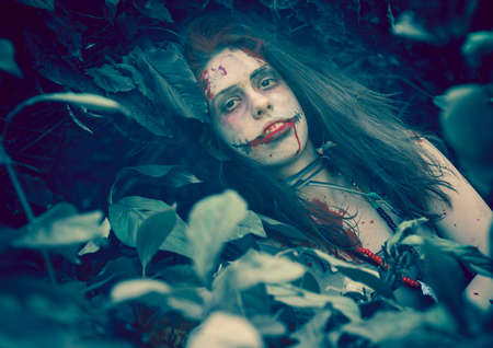 Woman zombie portrait outdoors. Dark lighting. Color was changed to emphasize the atmosphere of horror.の写真素材