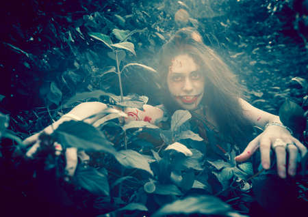 Woman zombie portrait outdoors. Dark lighting. Color was changed to emphasize the atmosphere of horror.の写真素材