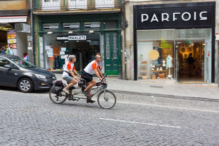 PORTO, PORTUGAL - JUNE, 12: Mature couple ride tandem bicycle in old city on June 12, 2015 in Porto, Portugalのeditorial素材