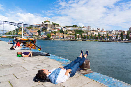 PORTO, PORTUGAL - JUNE, 14: Tourists relax at the embankment near famous landmark Luis bridge at day time on June 14, 2015 in Porto, Portugalのeditorial素材