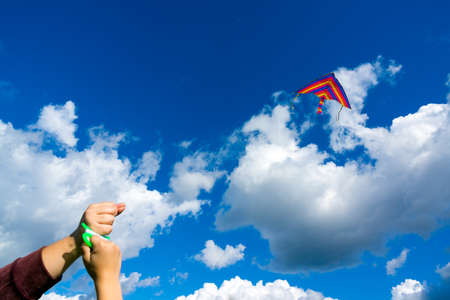 Hands holding kite in the cloudy sky. Focus to kiteの写真素材