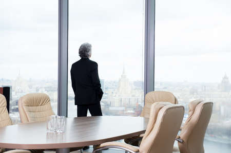 Middle age businessman looking out the window at the panorama of the cityの写真素材