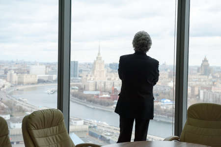 Middle age businessman looking out the window at the panorama of the cityの写真素材