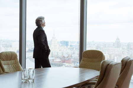 Middle age businessman looking out the window at the panorama of the cityの写真素材