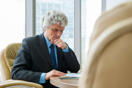 Mature business man works with docs in modern office