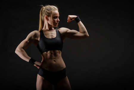 Young muscular woman posing on black backgroundの写真素材