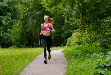 Young slim woman jogging in a parkの写真素材