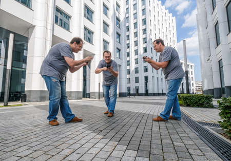 Man playing mobile game at the modern city backgroundの写真素材