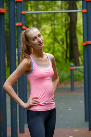 Young slim woman sports portrait on the training ground in a park
