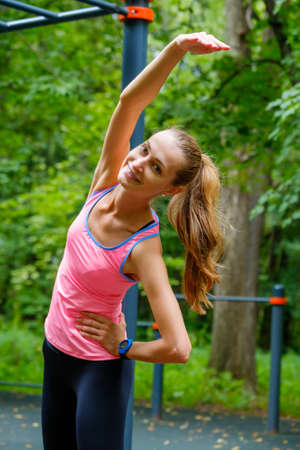 Young slim woman stretching in a training ground in a park
