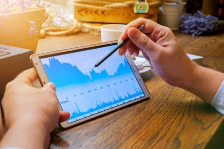 Business man works with graph on tablet pc with stylus in cafeの写真素材